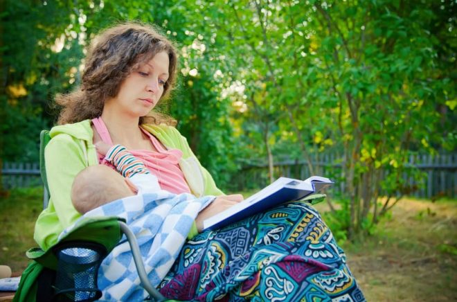 mother breastfeeding while reading the book