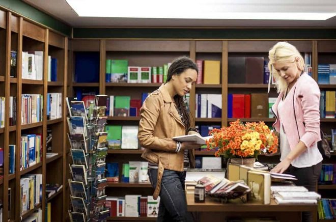 Two smiling women at a book shop together.