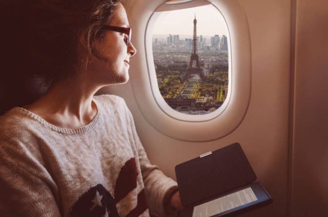 Smiling woman enjoying Paris from the airplane window