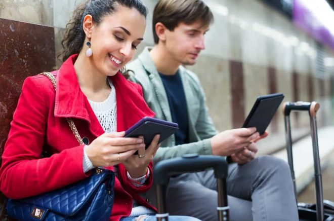 Subway passengers reading with modern gadgets as waiting the train