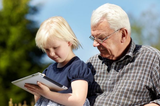 Old grandfather and little girl using touchpad e-book readers