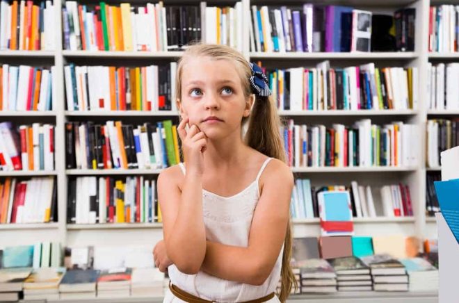 blond smart girl child bemused a lot of books in library