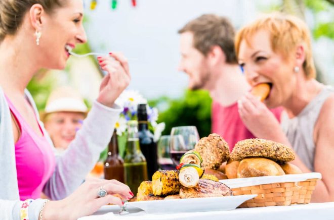 Friends eating bbq sausage and meat at garden or grill party