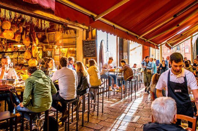 Bologna är en känt för sin gastronomi - och sin barnboksmässa. Här en uteservering i närheten på Pescherie Vecchie av matmarknaden i gamla stan. Foto: iStock. (Personerna på bilden har ingen koppling till artikeln)