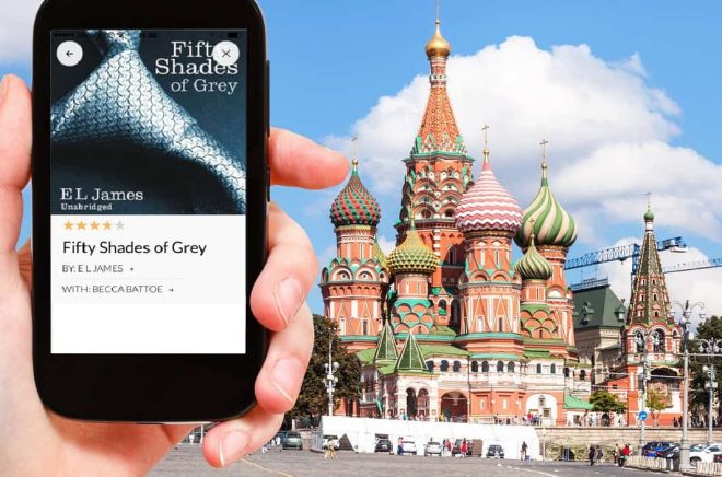 travel concept - hand holds smartphone with cut out screen and Saint Basil Cathedral on Moscoe Red Square on background