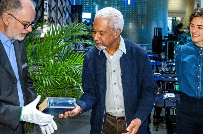 Litteraturpristagaren Abdulrazak Gurnah lämnar över sin ordbok till museets intendent Ulf Larsson under överinseende av museichefen Erika Lanner. Foto: Claudio Bresciani/TT