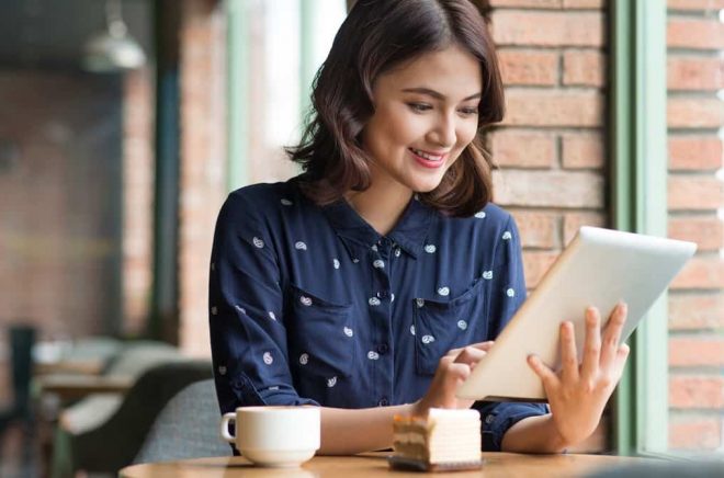 Beautiful cute asian young businesswoman in the cafe, using digital tablet and drinking coffee smiling