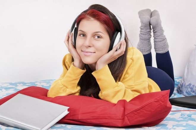 Music pause after study. Young girl in her bed relaxing with music after studying.