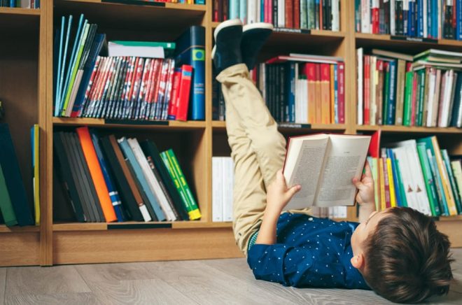 Läsande pojke på bibliotek. Foto: iStock.