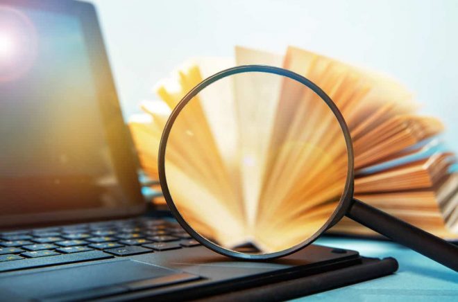 Laptop computer and book with magnifying glass, concept of search