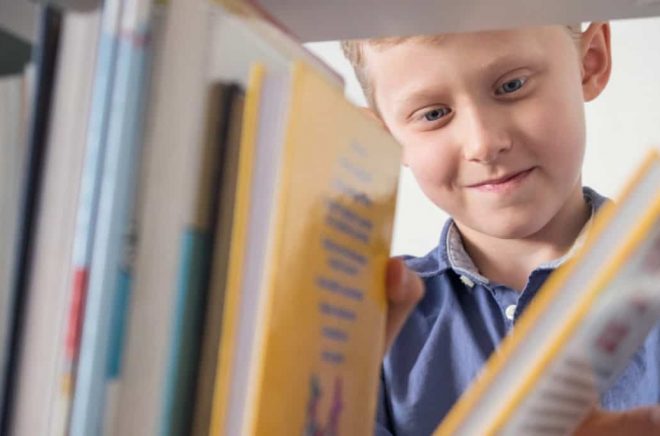 Cute little boy choose a book on the bookshelf