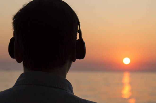 Young Man Is Watching Sunset While Listening Music