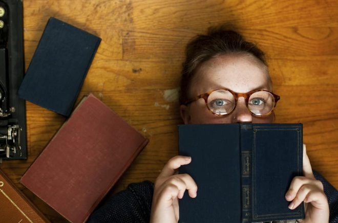 Horizontal portrait of a nerdy bookworm reading girl.