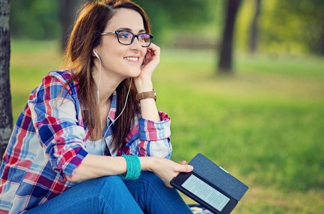 Young girl is reading from her ebook and listening music.